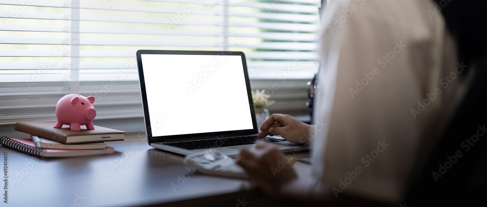 Laptop screen mock up, laptop in blank empty screen on the desk in home while woman working on financial calculating Laptop screen mock up, laptop in blank empty screen on the desk in home while woman working on financial calculating
