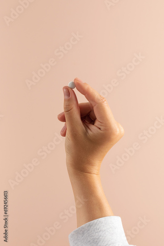 A woman's hand holds a pill with a medicinal supplement . Healthcare, food additives and medicines.