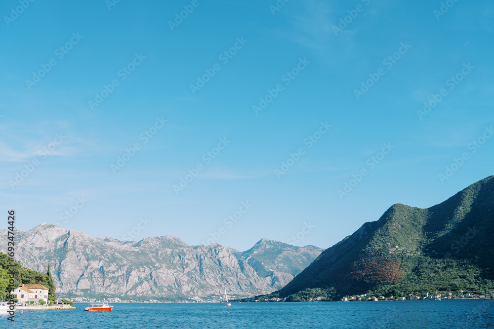 Red motorboat sails on a bay near a mountainous coast