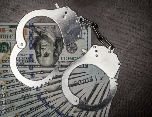 one hundred dollar bills and steel handcuffs close up photo