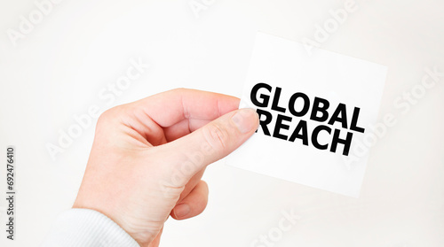 Businessman holding a card with text GLOBAL REACH, business concept