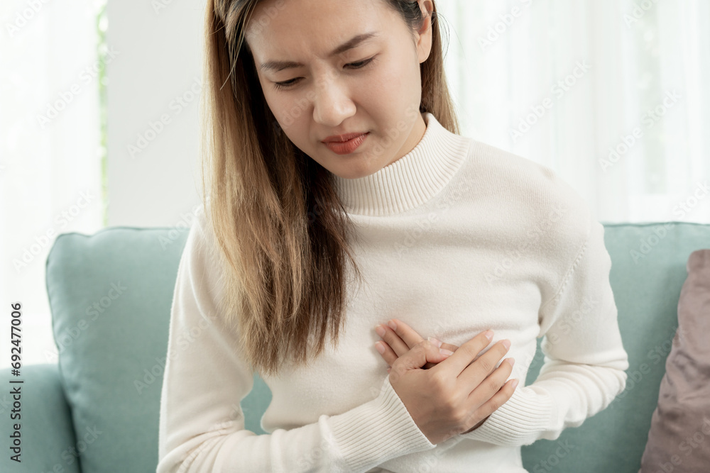 hand hold chest with heart attack symptoms, asian woman have chest pain caused by heart disease, leak, dilatation, enlarged coronary heart, press on the chest with a painful expression. hand hold chest with heart attack symptoms, asian woman have chest pain caused by heart disease, leak, dilatation, enlarged coronary heart, press on the chest with a painful expression.