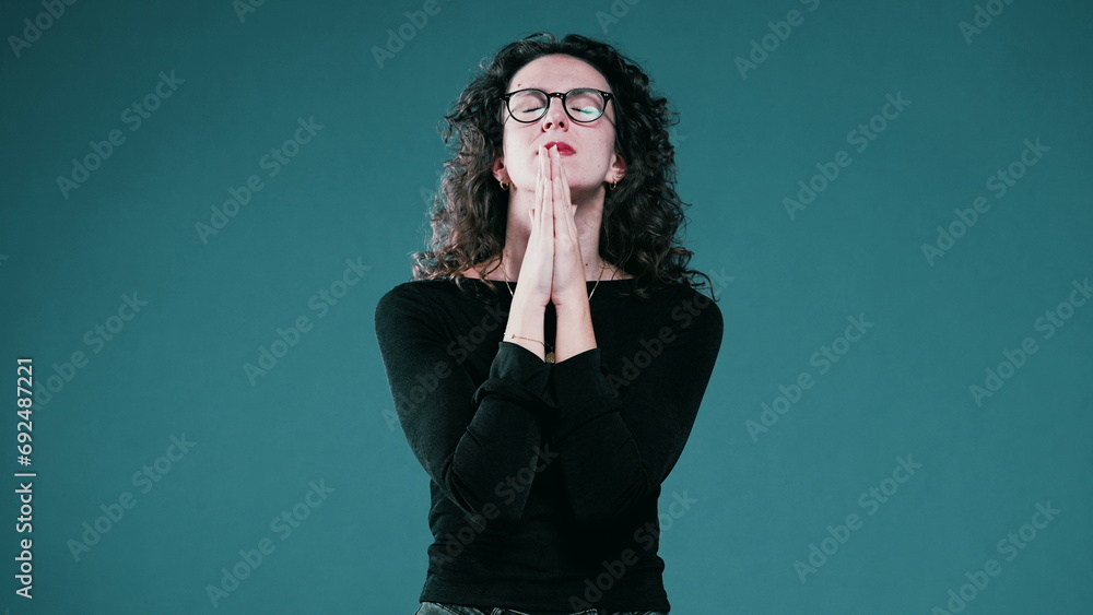 Woman closing her eyes holding her breath while Praying to God for help during difficult times, person seeking help and divine intervention Woman closing her eyes holding her breath while Praying to God for help during difficult times, person seeking help and divine intervention