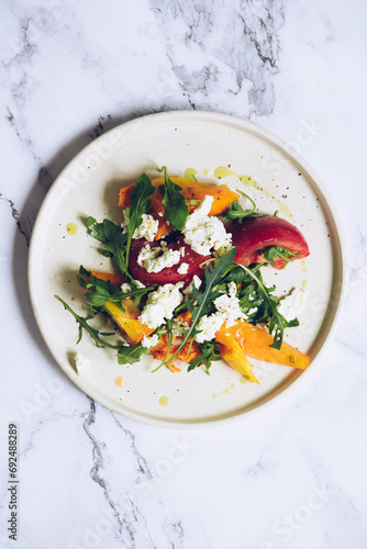 Healthy salad with different types of tomatoes, sweet potato, feta cheese and arugula