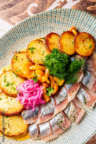 fish herring fillet with potatoes, nushrooms and onions on plate photo