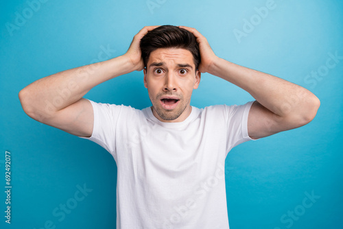 Photo of funky scared guy wear white t-shirt arms head open mouth isolated blue color background