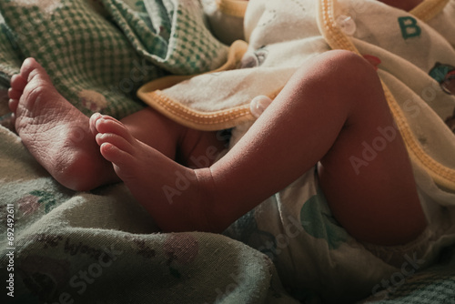 Close-up of unrecognizable cute baby shaking feet while lying in bed, innocence concept