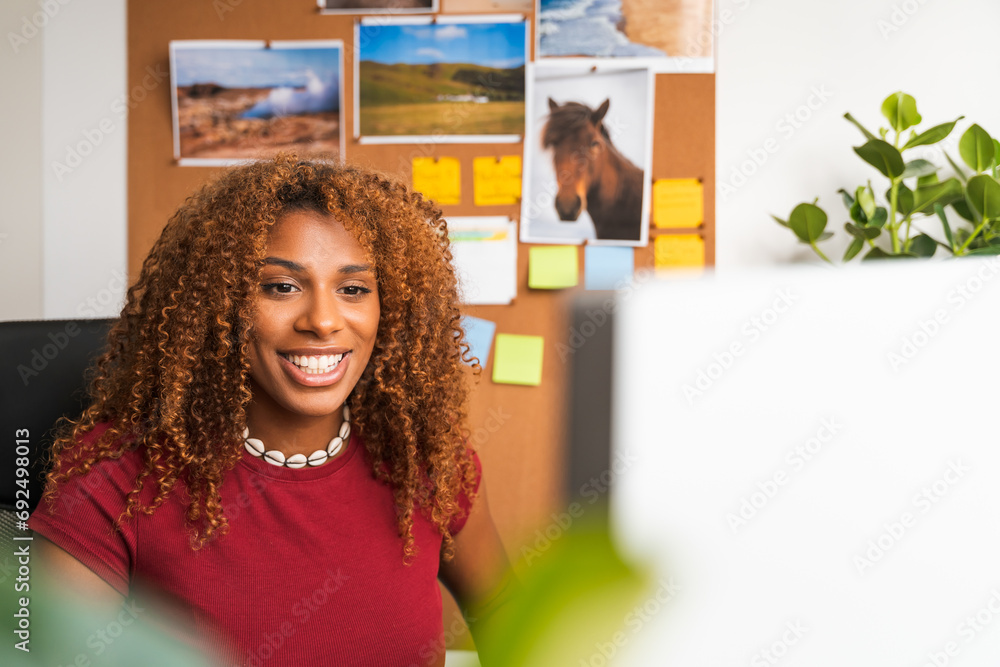 Happy curly woman looking at computer display with happy smile and working Happy curly woman looking at computer display with happy smile and working
