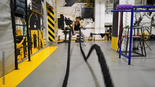 Wallpaper Mural Young muscular sportsman training with battle ropes at modern gym. Strong sporty man exercising in fitness club. Athletic guy doing hard and intense workout. Concept of sport and active lifestyle Torontodigital.ca