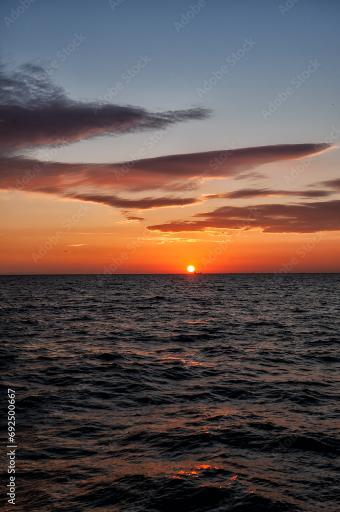 Beautiful sunset landscape with twilight sky, sun and sea water