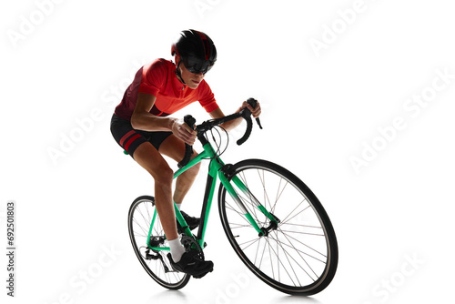 Muscular young man, athlete, cyclist in uniform and helmet, riding bicycle isolated over white studio background