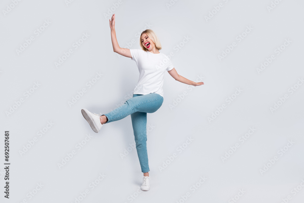 Full body photo of careless crazy eccentric woman wear stylish t-shirt jeans celebrate black friday isolated on gray color background Full body photo of careless crazy eccentric woman wear stylish t-shirt jeans celebrate black friday isolated on gray color background