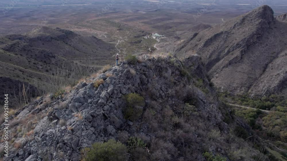 Aerial orbit of two hikers on top of a mountain peak Aerial orbit of two hikers on top of a mountain peak