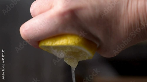 Closeup shot of person's hands squeezing lemon juice. Human squeezes half of lemon.