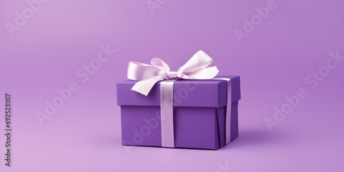purple gift box with silver ribbon bow isolated on purple pastel color background with emtpy copy space.