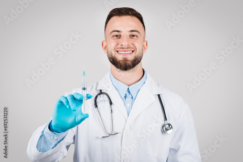 Cheerful male doctor holding a syringe  ready for vaccination