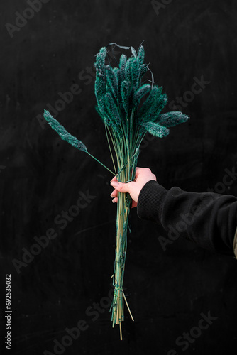 Bouquet of beautiful malachite flowers in a woman's hand on a background