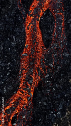 Vertical video of mesmerizing view of a lava flow, red hot molten liquid streaming over black solid volcanic rocks, aerial directly above shot. Abstract, texture, and background concepts.