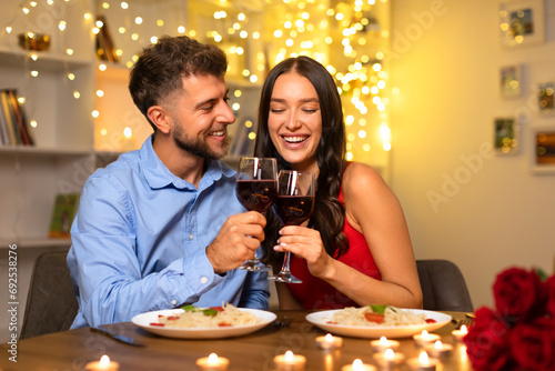 Foto Joyful couple toasting wine glasses at romantic dinner