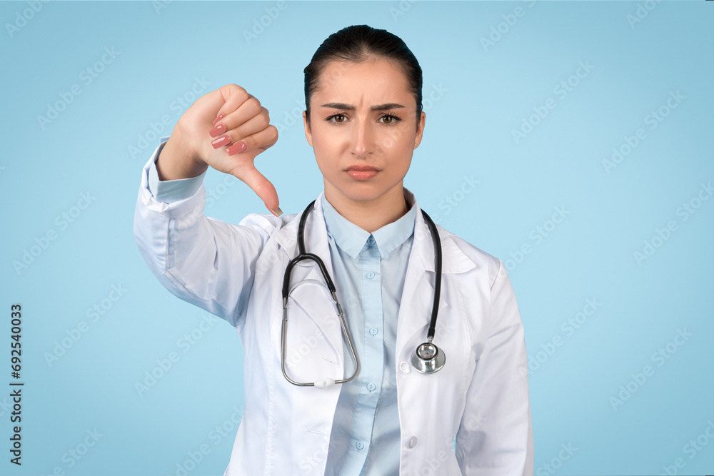 Disapproving female doctor giving thumbs down Disapproving female doctor giving thumbs down