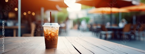 a plastic coffee cup cold coffee is placed on a wooden photo