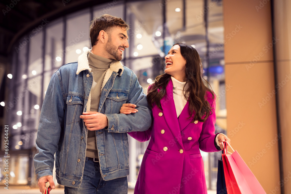 Young European couple enjoys festive winter shopping spree outside mall