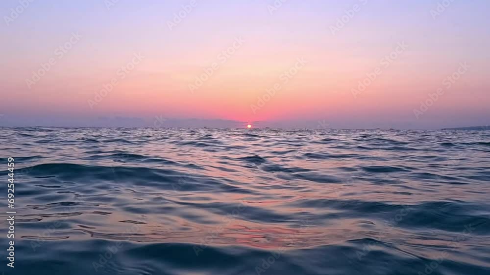 View from the surface of the sea at sunset. Chilling on the sea waves and watching the setting sun go below the horizon View from the surface of the sea at sunset. Chilling on the sea waves and watching the setting sun go below the horizon