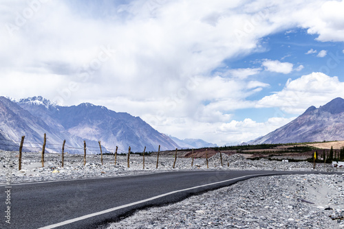 Splendid view of beautiful mountain road with white clouds and blue sky in the background.