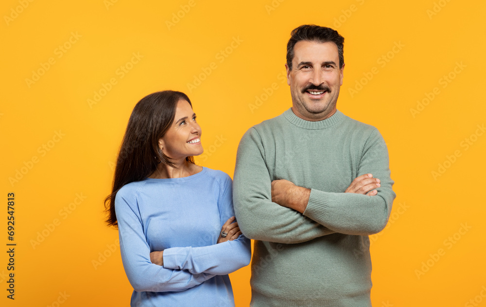 Smiling european old man and woman stand side by side against vibrant orange background Smiling european old man and woman stand side by side against vibrant orange background