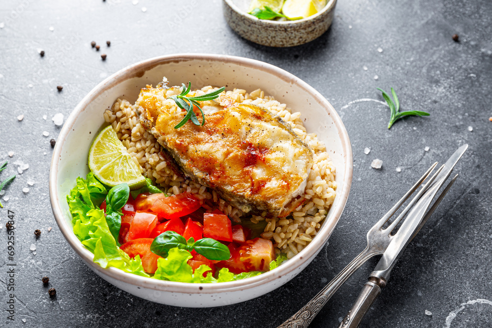 Fried catfish steak with rice and vegetable salad on a gray background Fried catfish steak with rice and vegetable salad on a gray background