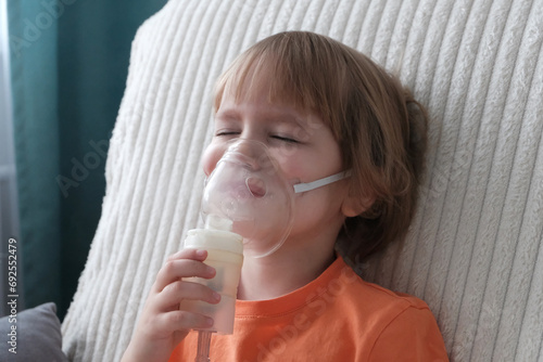 A little girl, a child of European appearance, blond hair, wearing an inhaler mask. Treatment of seasonal diseases with a nebulizer at home.