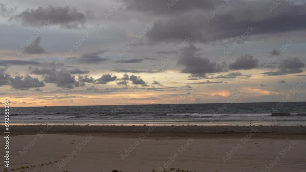 Sunset on a tropical beach. The waves of the ocean roll onto the shore. The sun has disappeared. Twilight. The sky is painted in gold and pink colors. Pale purple clouds. Reflection on wet sand. Sunset on a tropical beach. The waves of the ocean roll onto the shore. The sun has disappeared. Twilight. The sky is painted in gold and pink colors. Pale purple clouds. Reflection on wet sand.