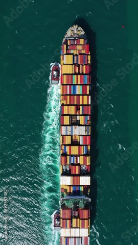 Large Container Ship and Tug Boat in Sea. Aerial Top-Down View. Drone Flies Sideways and Upwards. Vertical Video photo