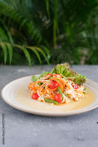 Thai food  Papaya salad on white plate on grey background