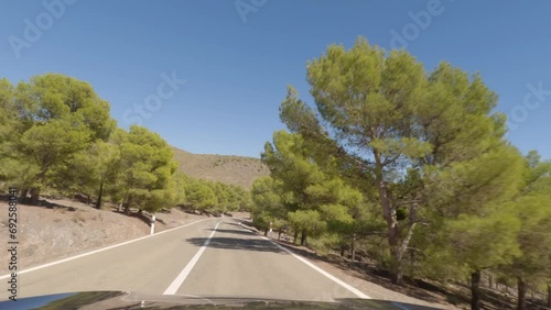 First person view, FPV, from dashcam of car driving mountain road from Calar Alto Observatory to Tabernas Desert in Almeria, Andalusia, Spain, Europe. Road trip in POV, with cyclist passing by photo