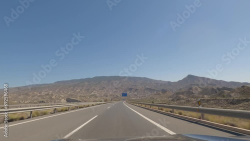 First person view from dashcam of car driving empty roads in the Tabernas desert in Almeria, Andalusia, Spain. Setting of spaghetti western films. Road trip video in POV, with bright, sunny, clear sky photo