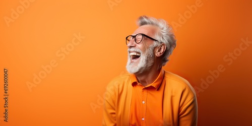 Expressive portrait of a senior man, laughing heartily, against a vivid orange background , concept of Joy