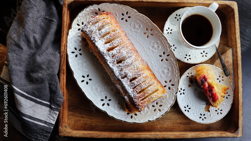 Traditional freshly baked whole apple strudel on wooden table, close up. Fresh homemade pastries with fruit or berry filling photo