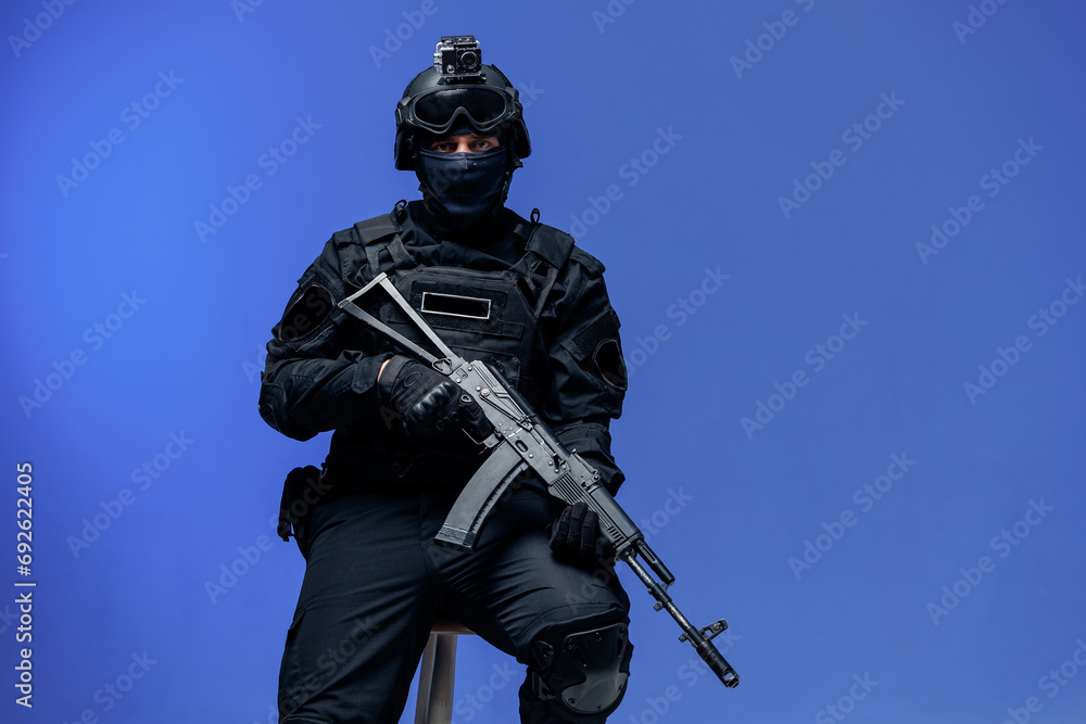Portrait soldier in black uniforms in studio, blue background. Concept Military warrior army tactical force to fight crime in city