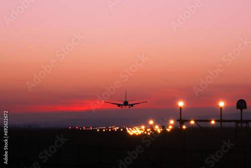 Plane lands at an airfield on the background of red clouds