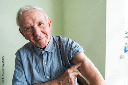 Happy old grandfather at his home. An adult pensioner sits against a wall with a bandage after vaccination. photo