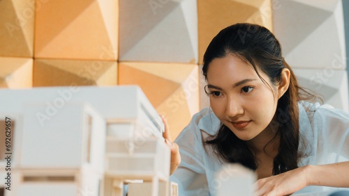 Portrait of professional asian female architect engineer looking while checking at house model at office. Checking real estate house. Business design and building construction concept. Manipulator.