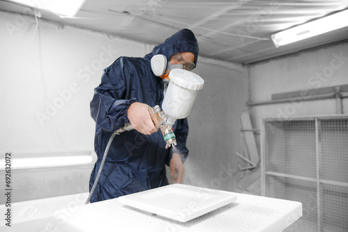 Professional worker staining wood furniture with spray gun photo