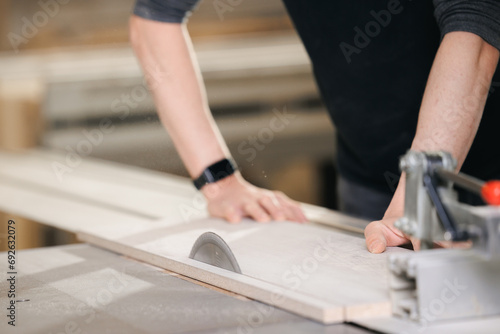 Closeup of wood cut table with electric circular saw for chipboard for furniture production. Professional carpenter cutting wooden board at sawmill