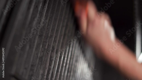 Close-up of a man's hands using a metal brush to clean a dirty grill photo