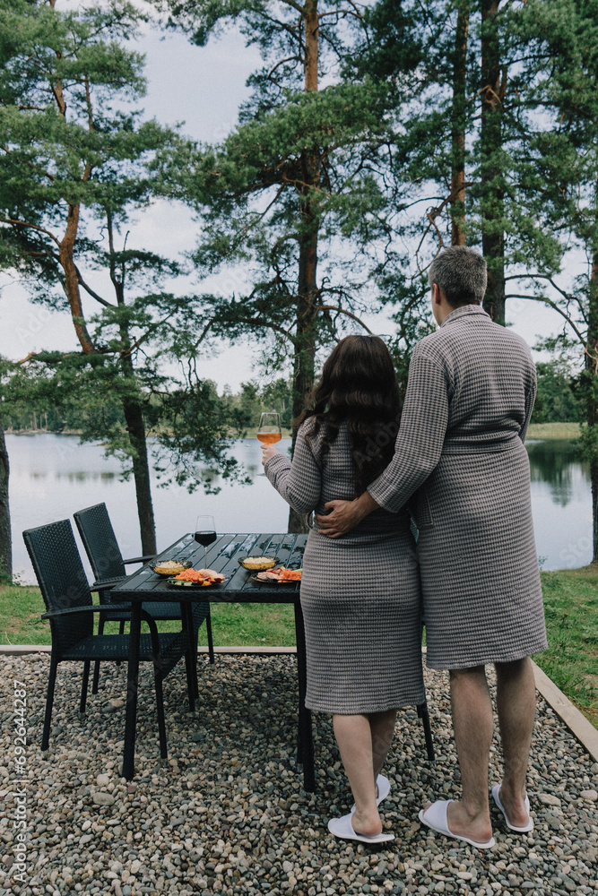 A man and woman standing next to a table with food on it. A man and woman standing next to a table with food on it.