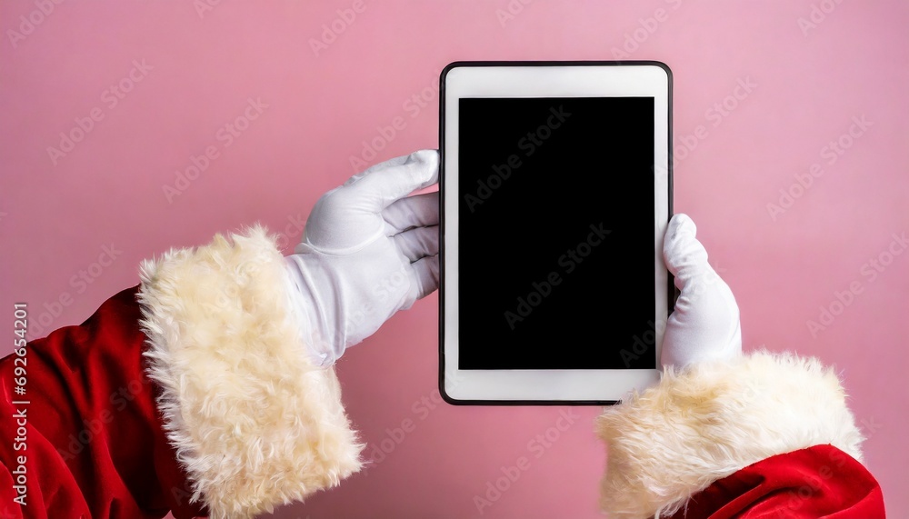 Image of hands of santa claus holding tablet with blank screen and copy space on pink background Image of hands of santa claus holding tablet with blank screen and copy space on pink background