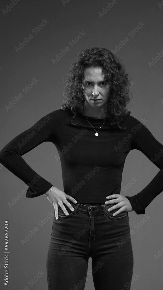 Stern serious woman looking at camera feeling angry, puts hands on hips looking directly at camera in black and white, vertical video Stern serious woman looking at camera feeling angry, puts hands on hips looking directly at camera in black and white, vertical video