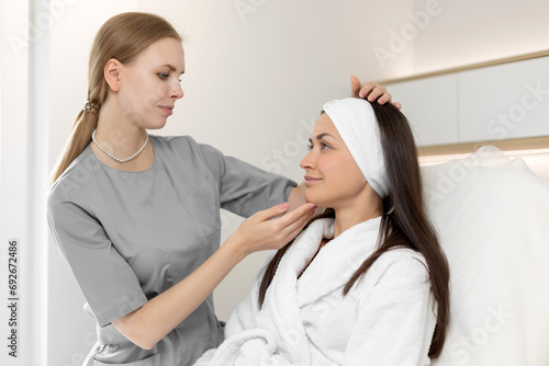 A beautician advises a woman on facial skin care in a beauty salon