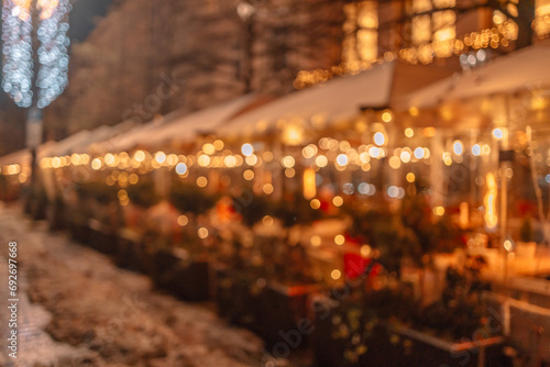 Decorative outdoor string lights at night time. Blurred background of outdoor restaurant with abstract bokeh light during Christmas holidays of night festival..